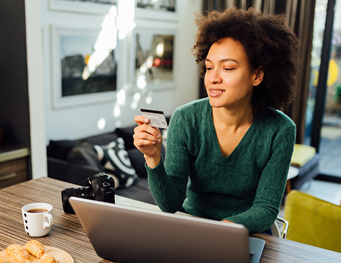 Woman making debit card payment from home computer